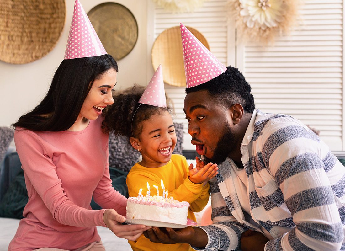 About Our Agency - Happy Mother and Daughter Celebrate a Birthday With Dad at Home